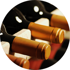Close-up of wine bottles with gold foil capsules lying on their sides in a wooden rack