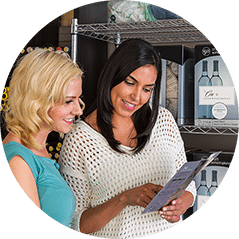 Two women in a winemaking store reading a wine kit instruction leaflet together