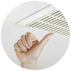 A hand giving a thumbs up beneath a white ceiling ventilation vent