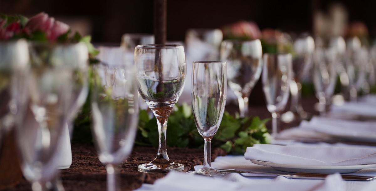Long banquet table set with wine glasses, white napkins and floral centrepieces for a special occasion